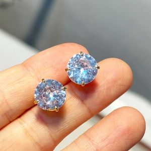 Detailed view of classic four-prong gold-plated earrings with light blue round zircons