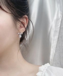 Detailed close-up of a silver bow earring with sparkling moissanite on a model