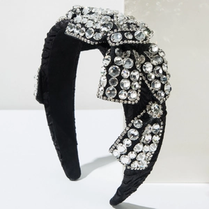 Détail d'un serre-tête large en velours noir avec un grand nœud orné de strass brillants