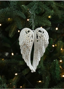 Close-up of white and gold glitter angel wing ornament hanging on a Christmas tree