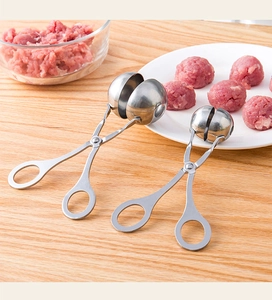 Macro shot of stainless steel meatball maker tool on kitchen table with raw meat ingredients