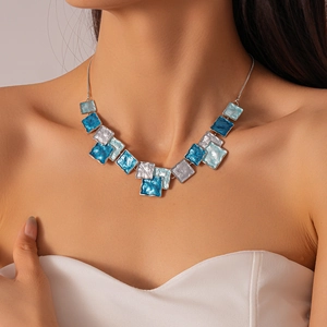 Detail of blue and silver geometric enamel pendant necklace on model collarbone