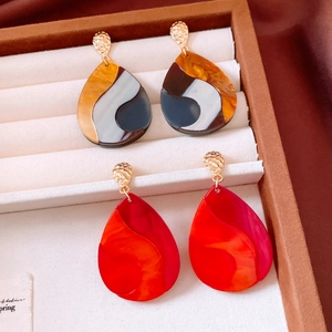 Détail macro de boucles d'oreilles gouttes en résine avec texture en métal martelé doré