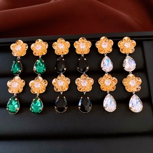 Vue macro de boucles d'oreilles fleurs en or 18K avec cristaux verts, noirs et clairs