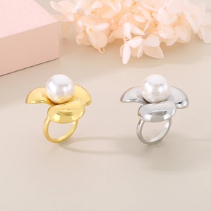 Elegante anello a fiore con grande perla in finiture oro 18K e argento su sfondo beige