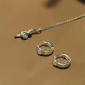 Macro shot of silver knot pendant necklace and white pearl hoop earrings set