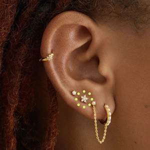 Macro view of gold plated silver ear piercings with pearls and chain drop earrings