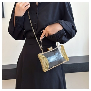 Close-up of a clear acrylic evening bag with gold rhinestones and metallic chain strap