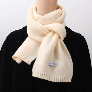 Close-up of beige ribbed knit scarf with professional FEID brand tag on soft wool texture
