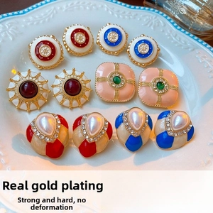 Detailed macro of vintage French enamel earrings featuring gold plating and faux pearls