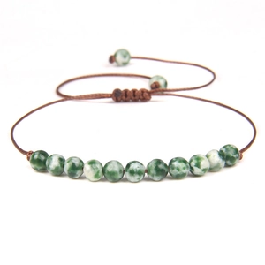 Macro shot of 4mm marble-patterned stone beads on an adjustable woven bracelet cord
