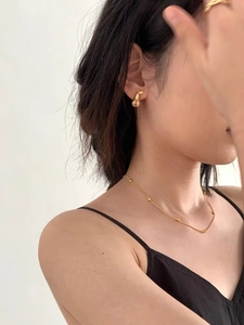 Detail showing elegant gold beaded necklace and leaf-shaped earrings on model neck