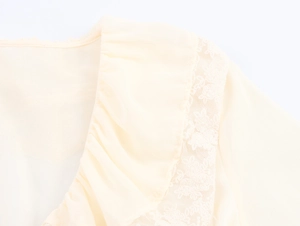 Close-up of ruffled V-neckline with lace stitching on a beige chiffon French style dress