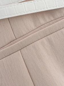 Close-up of pink twill fabric texture and white croc-effect leather belt detail