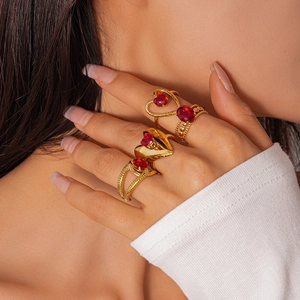 Dettaglio di quattro anelli d'oro con pietre rosse a cuore su una mano per un look retro