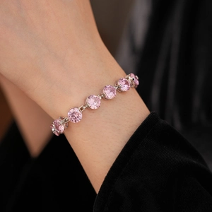 Detailed view of tennis bracelet with pink round-cut cubic zirconia in silver setting