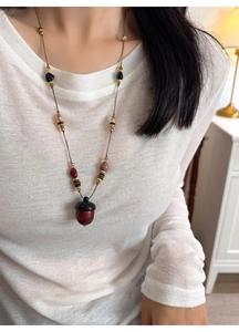 Close-up of ethnic acorn pendant necklace with colorful beads on white sweater