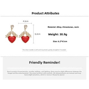 Gros plan des boucles d'oreilles cœur rouge avec résine, ailes en strass et dimensions