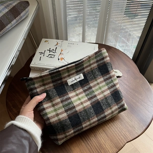 Close-up of vintage plaid wool makeup bag with black zipper and simple wish label