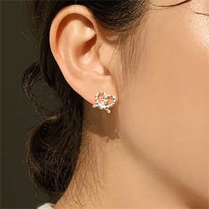 Close-up of twisted silver heart stud earrings with knot detail worn by a model