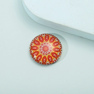 Macro detail of round glass mandala fridge magnet with vibrant red and yellow floral patterns