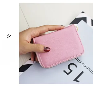 Close-up of pink litchi grain leather card wallet with a golden metal zipper closure