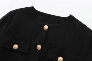 Detail of black tweed jacket featuring gold embossed buttons and textured woven fabric
