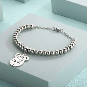 Detailed view of silver bead bracelet with hollow pig pendant on blue display