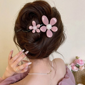 Detail of pink resin flower hair clip with pearl center on black curved hairpin