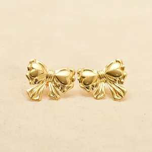 Elegant 18K gold plated stainless steel bow knot stud earrings for women on beige texture