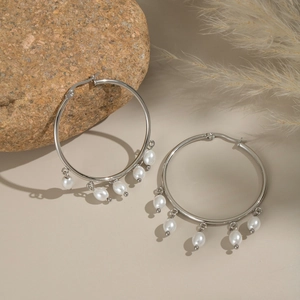 Detail of silver hoop earrings featuring hanging white pearls and natural stone decor