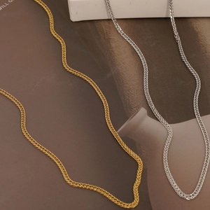 Minimalist stainless steel wheat chain necklaces in gold and silver on a magazine