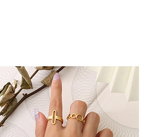 Close-up of golden geometric hollow ring on finger with elegant floral background