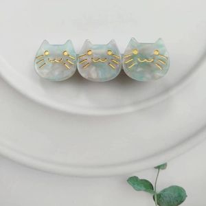Close-up of cute light blue marble pattern cat hair clip with gold facial details