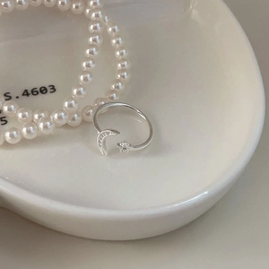 Close-up of 925 sterling silver open ring with pavé moon and star motifs on a ceramic tray