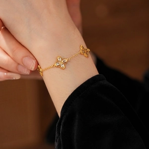 Elegant gold plated clover bracelet with sparkling zircons worn on woman's wrist