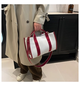 Detail of red and white contrast tote bag with lychee texture leather and long strap