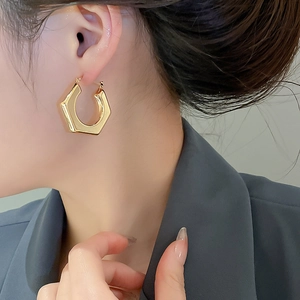 Polished gold hexagonal geometric hoop earring shown on model for size and fit