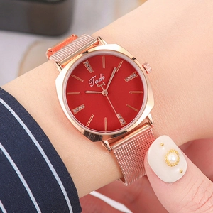 Detail of rose gold mesh band watch with a red dial and subtle crystal markers