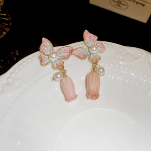Vue détaillée de boucles d'oreilles papillon dégradé et tulipe rose avec perles fines