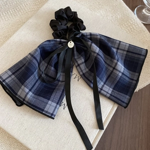 Detail of blue plaid bow hair tie with black satin ruffles and silver metal charm
