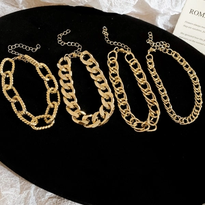 Detail of four gold chain bracelets with lobster clasps and extendable links on black base