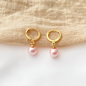 Detail view of round gold hoop earrings featuring elegant hanging pink shell pearls