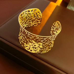 Detailed view of the irregular hollow surface on the wide gold open cuff bracelet