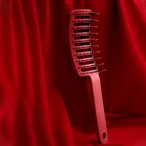 Curved vent hairbrush with boar bristles for volume styling on red velvet background