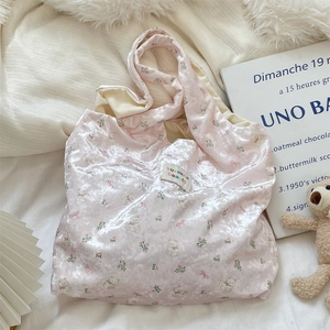 Close-up of pink velvet shoulder bag featuring cute bear print and brand label detail