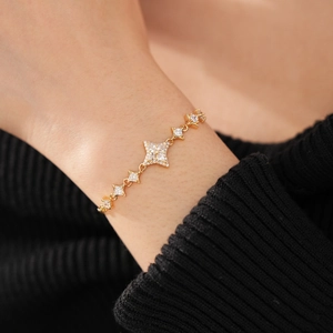 Macro shot of gold compass star bracelet with micro-paved zircons on a model's wrist