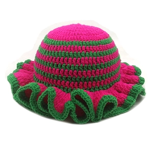Macro detail of handmade crochet ruffle hat featuring vibrant pink and green wool knit texture