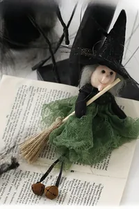 Detail of Halloween flying witch doll with green mesh dress and broom on a vintage book