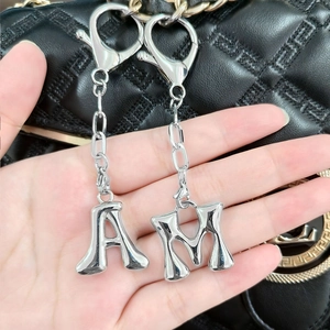 Polished silver alphabet keychain with A and M charms on a black quilted bag